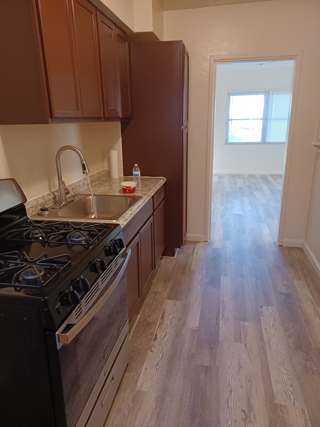 A kitchen with a black stove top oven and wooden cabinets.