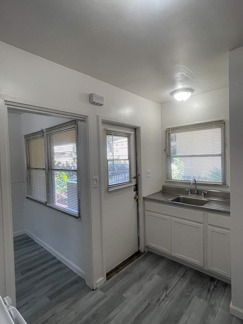 A small white bathroom with a sink and a window.