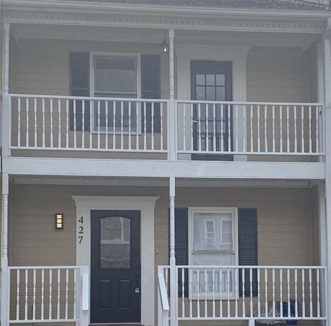 A two story house with a black door and white railings.