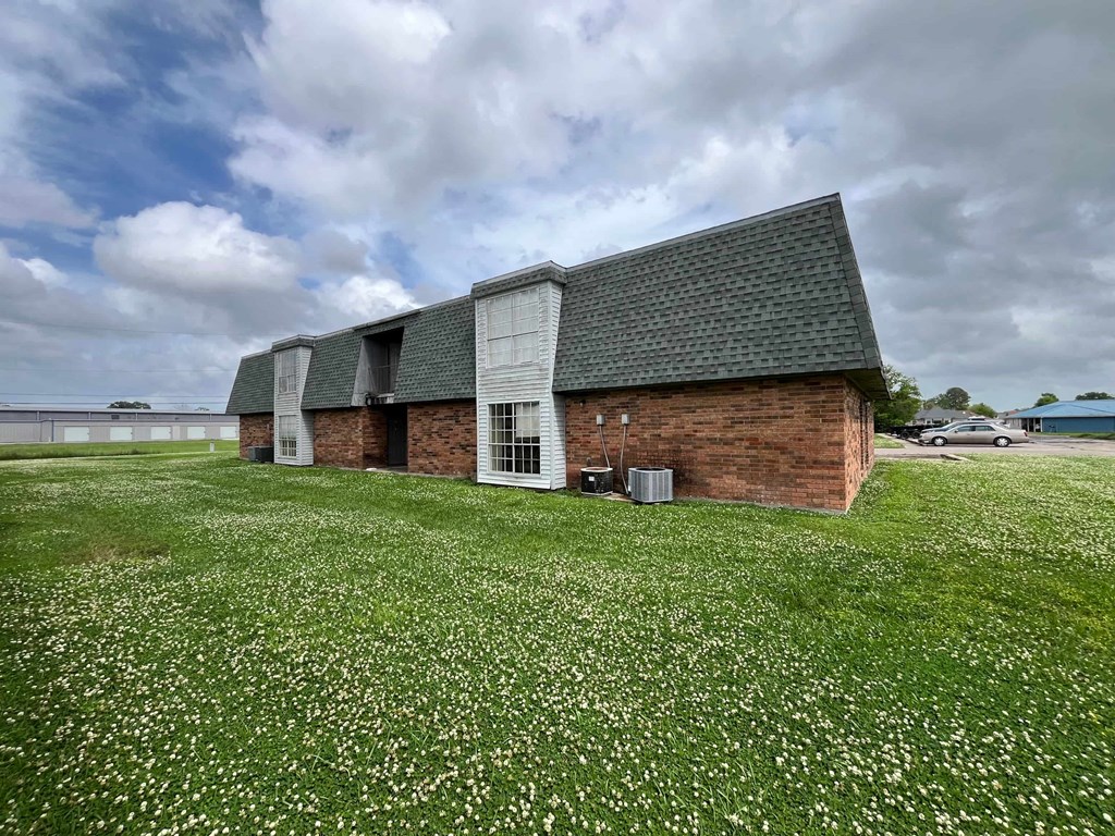 A building with a green roof and a white door is surrounded by a field of white flowers.