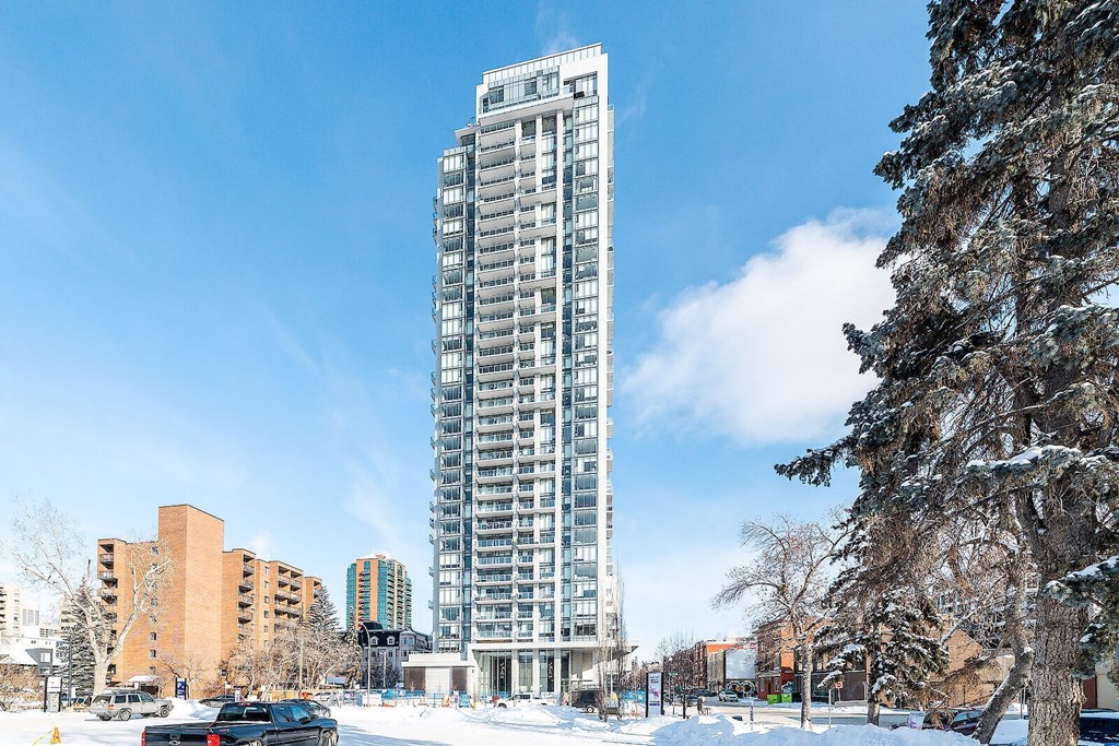 A tall building stands in the snow next to a tree.