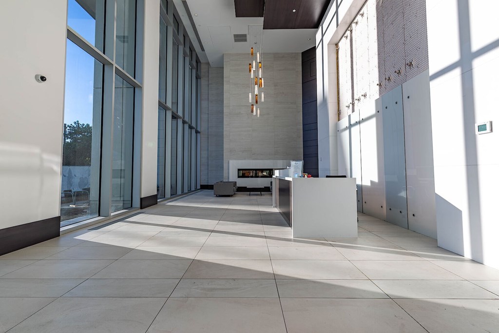 A modern lobby with a white reception desk and a large window.