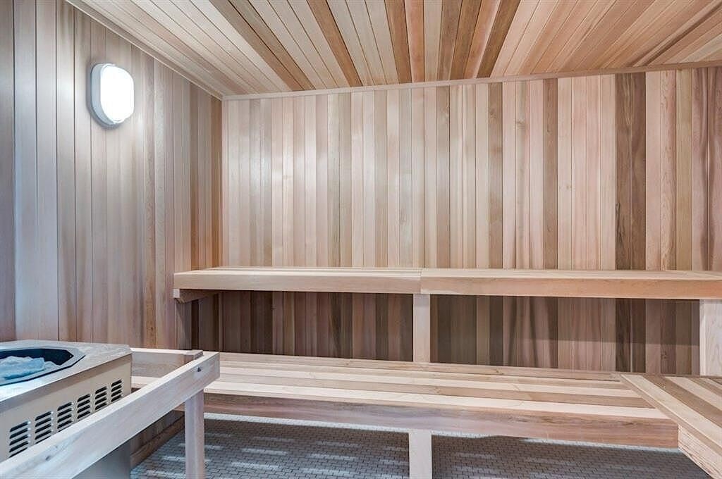 A wooden sauna with benches and a light on the wall.