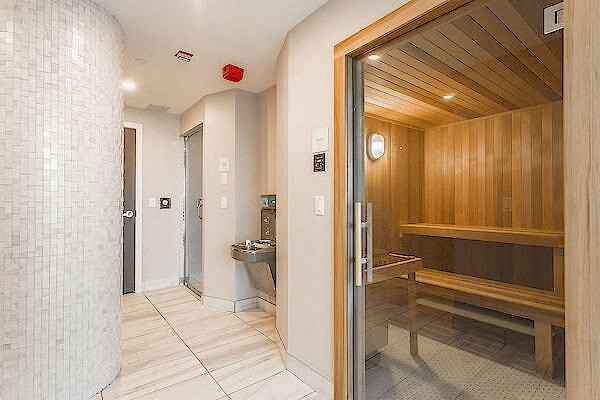 A bathroom with a wooden bench and a glass shower door.
