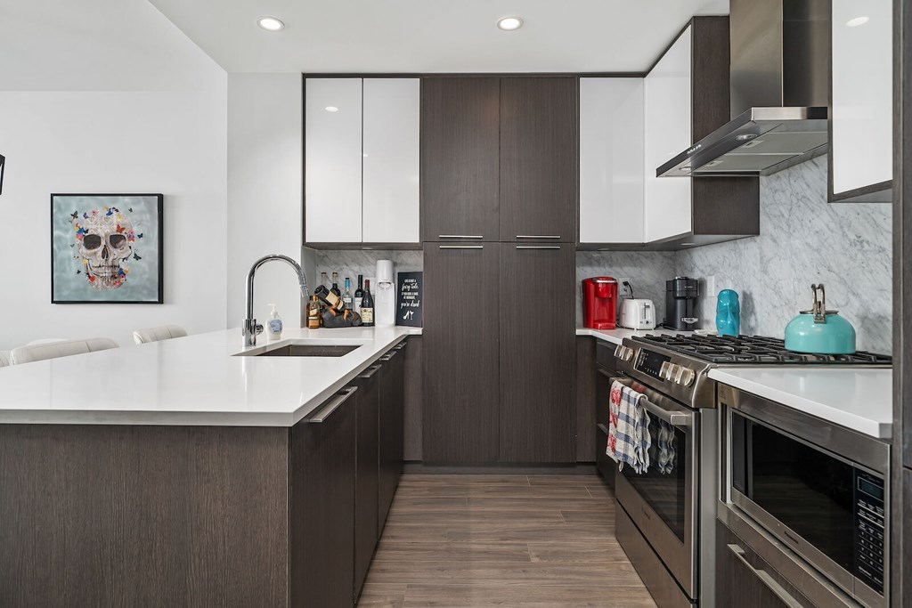 A modern kitchen with dark wood cabinets and stainless steel appliances.