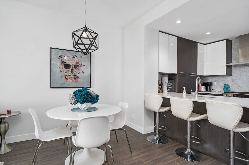 A dining room with a white table and chairs and a skull picture on the wall.