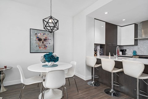 A dining room with a white table and chairs and a skull picture on the wall.