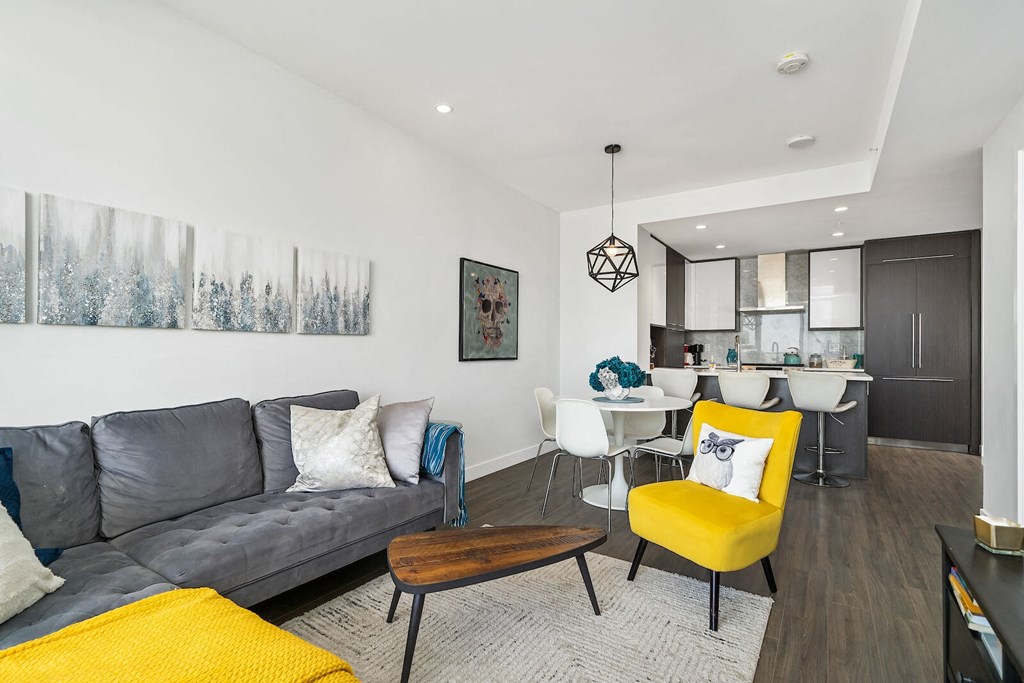 A living room with a grey couch, a yellow chair, and a painting on the wall.