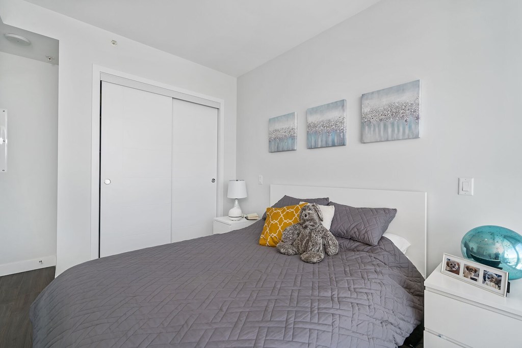 A bedroom with a bed, a nightstand, and pictures on the wall.