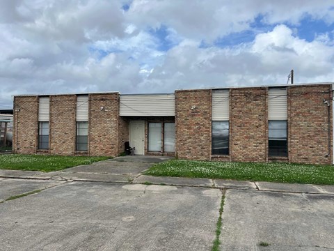 A brick building with a grey roof and a white door.