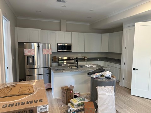 A kitchen with a refrigerator, microwave, and oven.