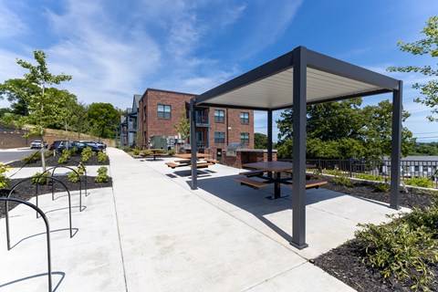 A covered picnic area with benches and a playground in the background.