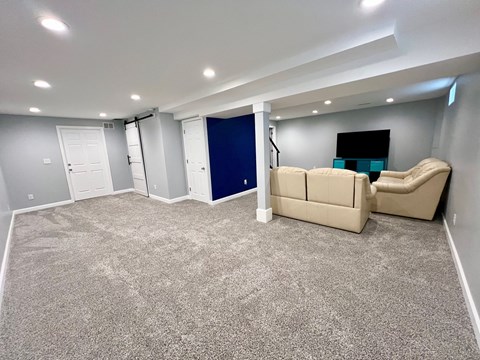 A spacious room with a carpeted floor and a blue door.