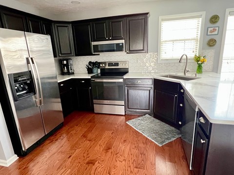 A kitchen with black cabinets and a wooden floor.
