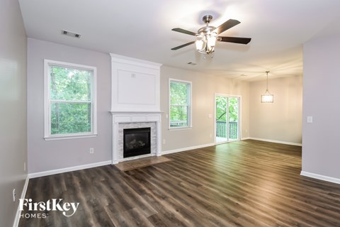 A spacious room with a fireplace and wooden flooring.