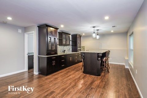 A kitchen with wooden floors and a black cabinetry.