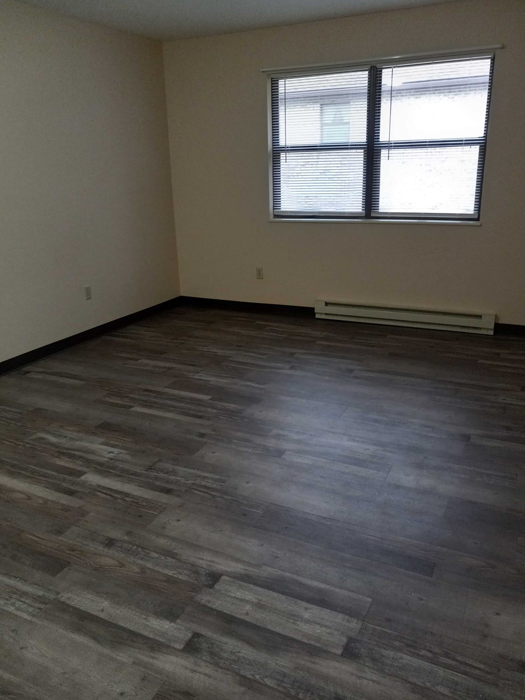 A room with a window and wooden flooring.