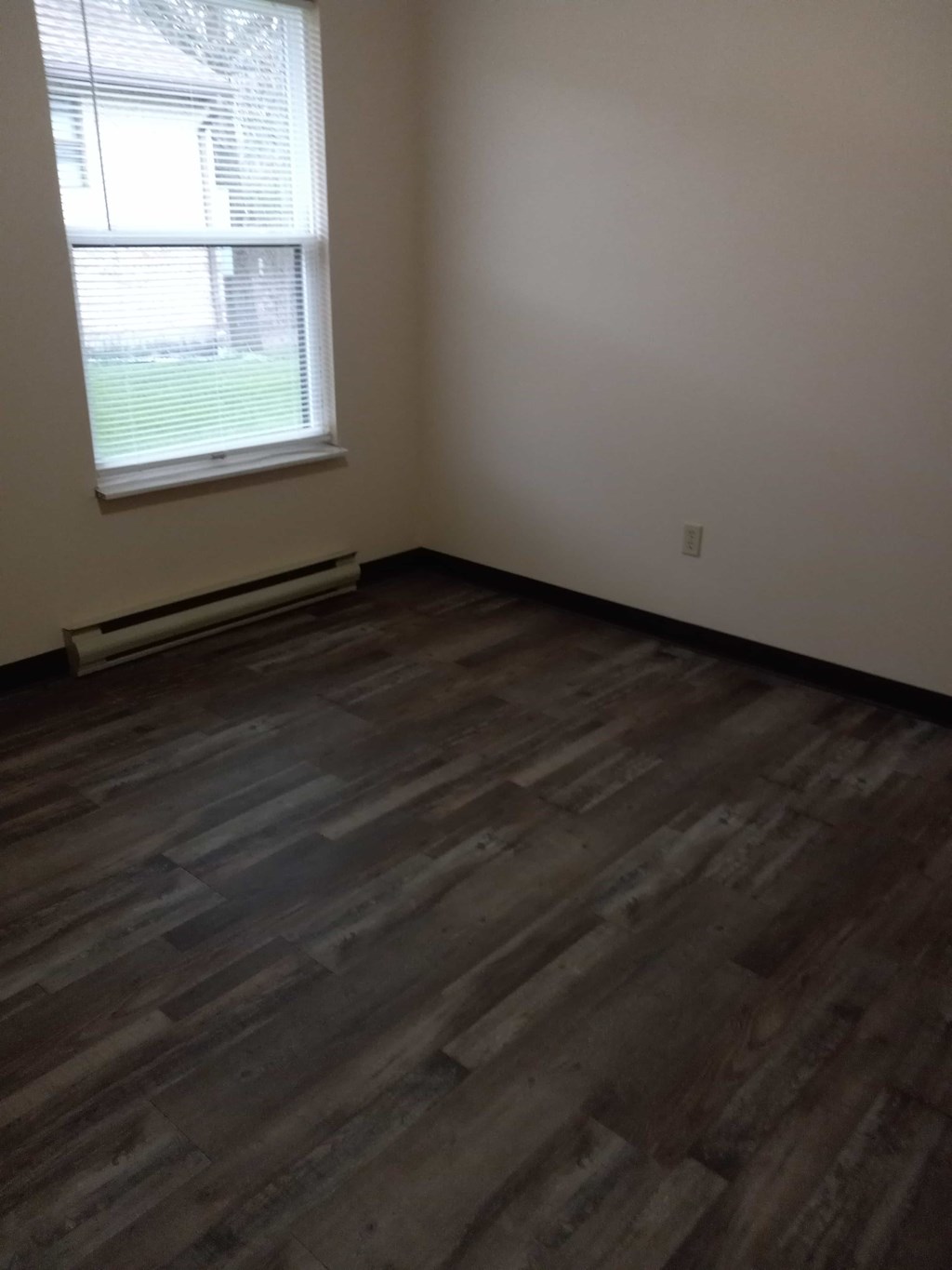 A room with a window and a wooden floor.