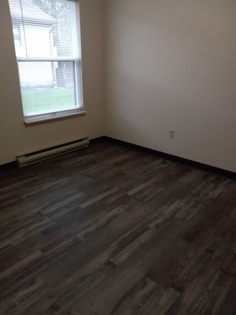 A room with a window and a wooden floor.