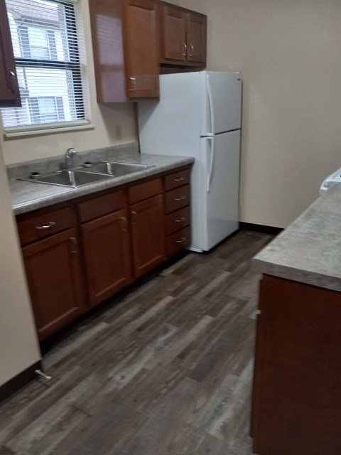 A kitchen with a white fridge and wooden cabinets.
