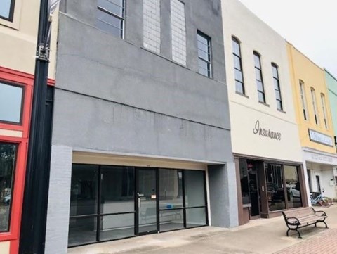 A grey building with a black pole in front of it.