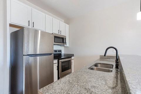 A kitchen with a granite counter top and stainless steel appliances.