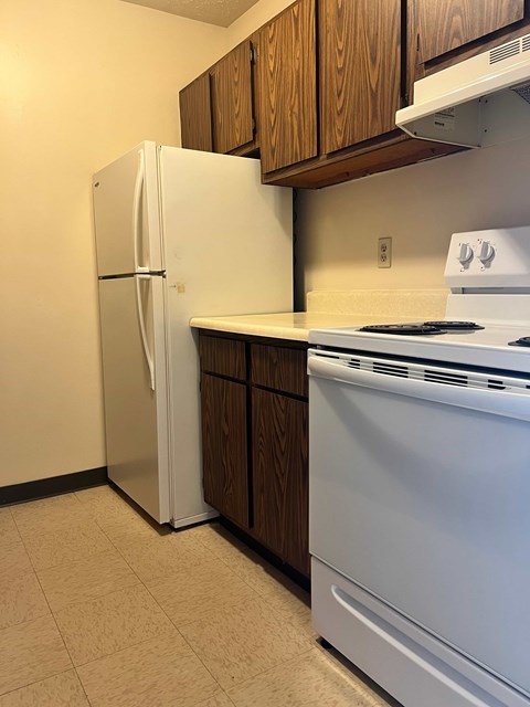 A white refrigerator stands next to a white stove in a kitchen.
