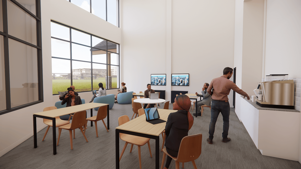 A man is standing in a room with tables and chairs and a laptop on one of the tables.