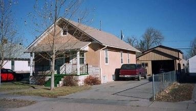 A house with a brown roof and a red car parked in front.