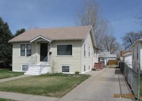 A beige house with a brown roof and a white fence.
