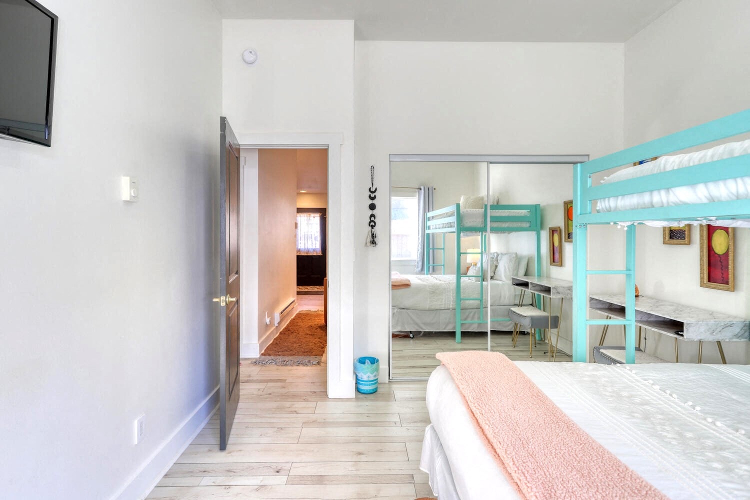 A bedroom with a bed, a TV, and a mirror.