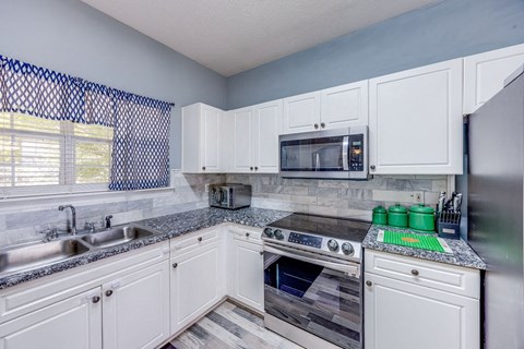 A kitchen with white cabinets and a black and white checkered curtain.