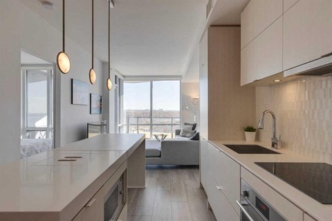 A modern kitchen with a large island and pendant lights.