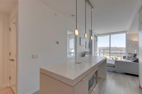 A modern kitchen with a large island and pendant lights.