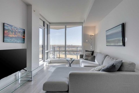 A modern living room with a grey couch and a glass table.