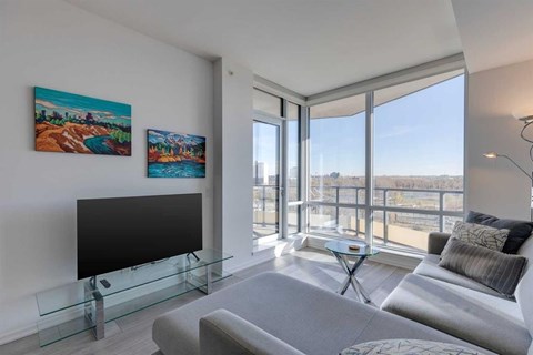 A living room with a grey couch and a black television.
