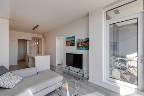 A living room with a grey couch and a glass table.