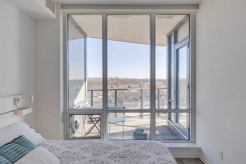 A bedroom with a large bed and a view of the outdoors through a sliding glass door.