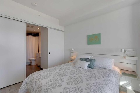 A bedroom with a large bed and a painting on the wall.