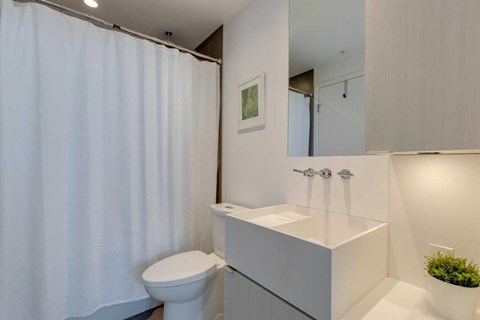 A white bathroom with a toilet, sink, and shower curtain.