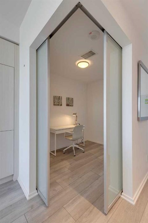 A white room with a desk and chair is visible through a glass door.