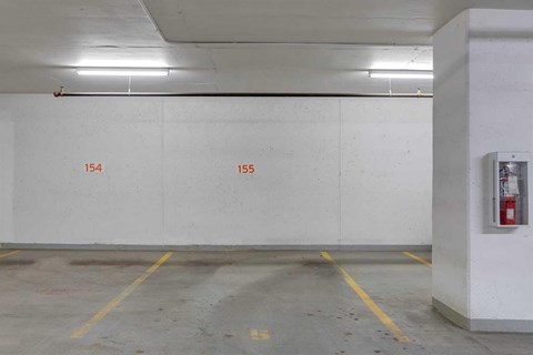 A parking garage with yellow lines and numbers 154 and 155 on the wall.