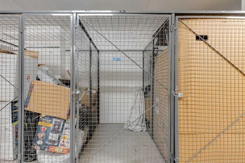 A metal cage with a wire mesh door is open, revealing a cluttered interior with various items.