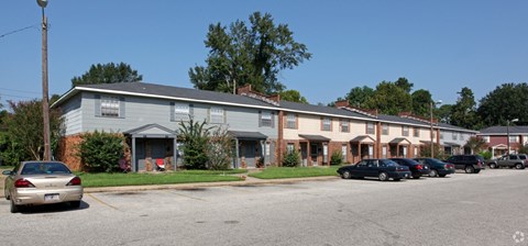 Apartment complex with a parking lot in front.