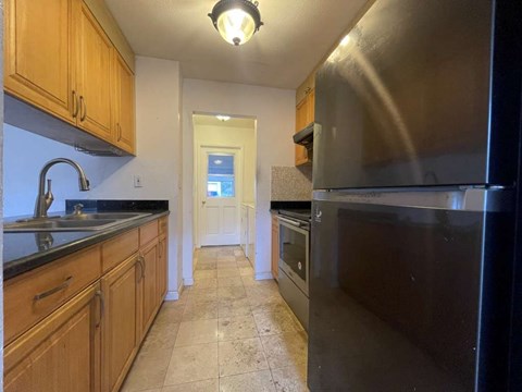 A kitchen with wooden cabinets and black appliances.