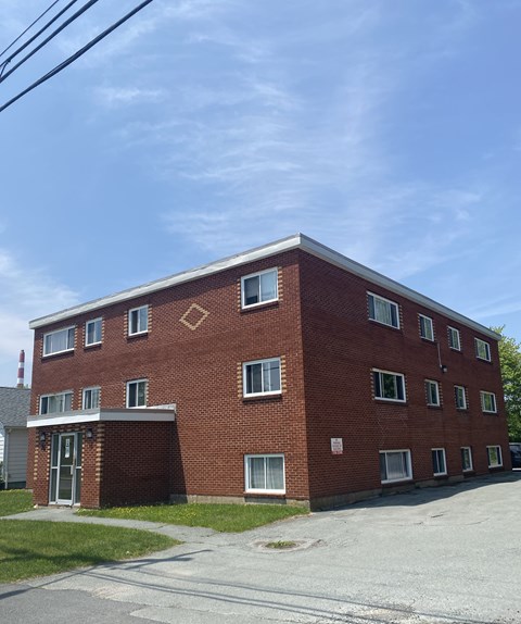 A red brick building with a white roof and a small porch.