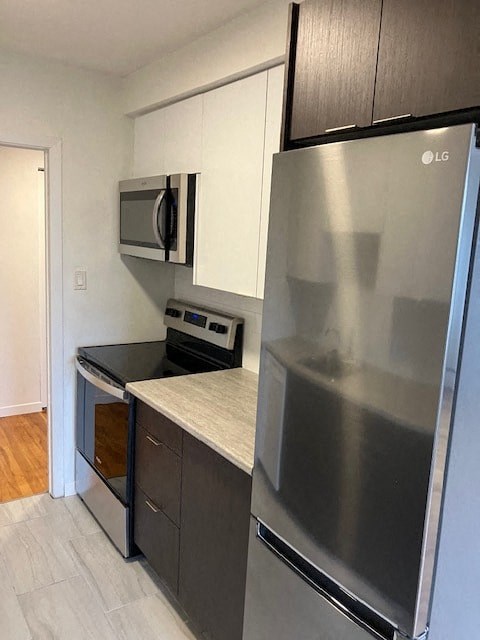 A modern kitchen with a stainless steel refrigerator and microwave above the oven.
