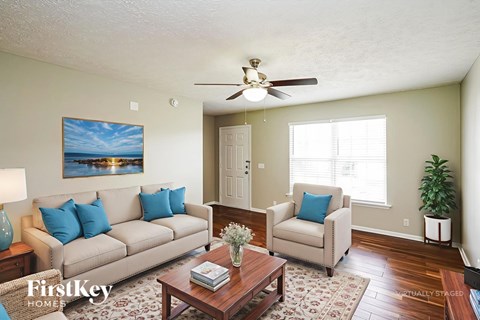 A living room with a couch, chair, and a painting of a beach scene on the wall.