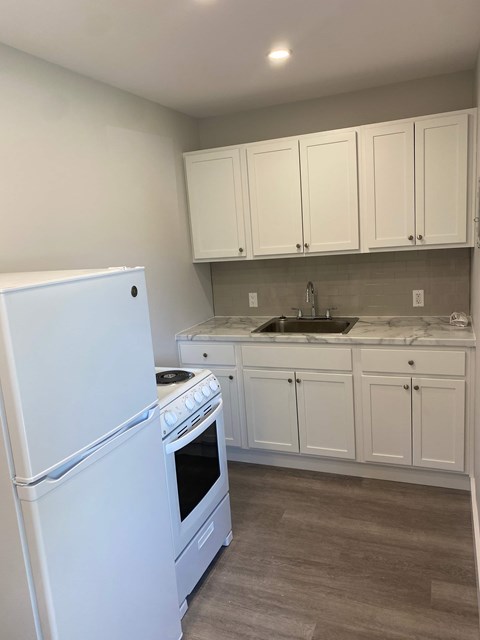 A white refrigerator and oven in a kitchen with white cabinets.