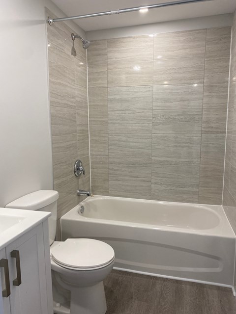 A white toilet sits next to a white bathtub in a bathroom.